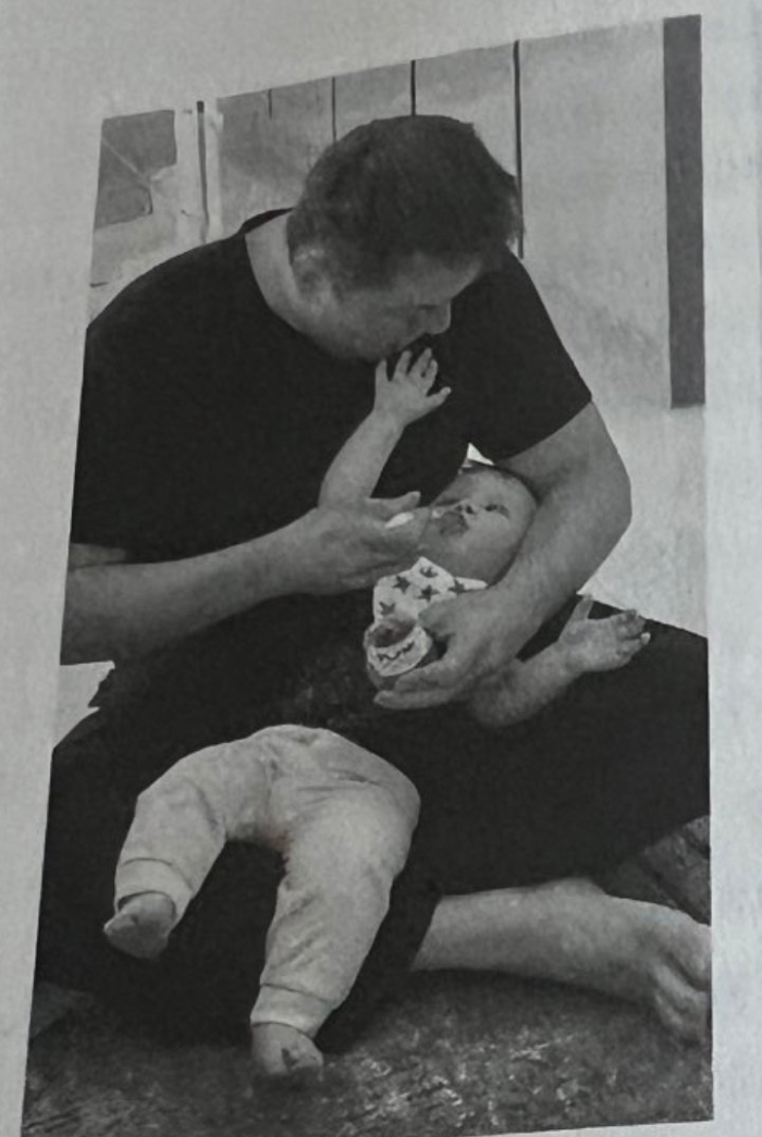 Man feeding a baby, highlighting Elon Musk&rsquo;s children and family life across multiple mothers and years.