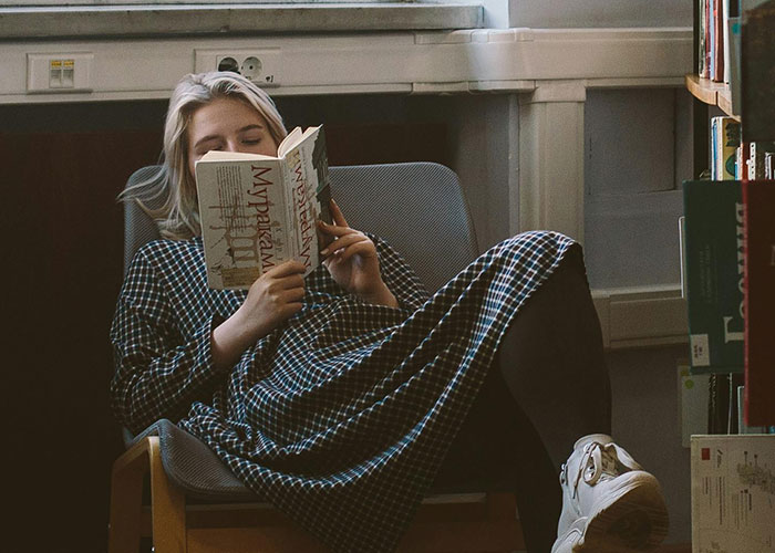 Person relaxing in a chair reading a book, representing experiences related to neurodivergent awareness and understanding.