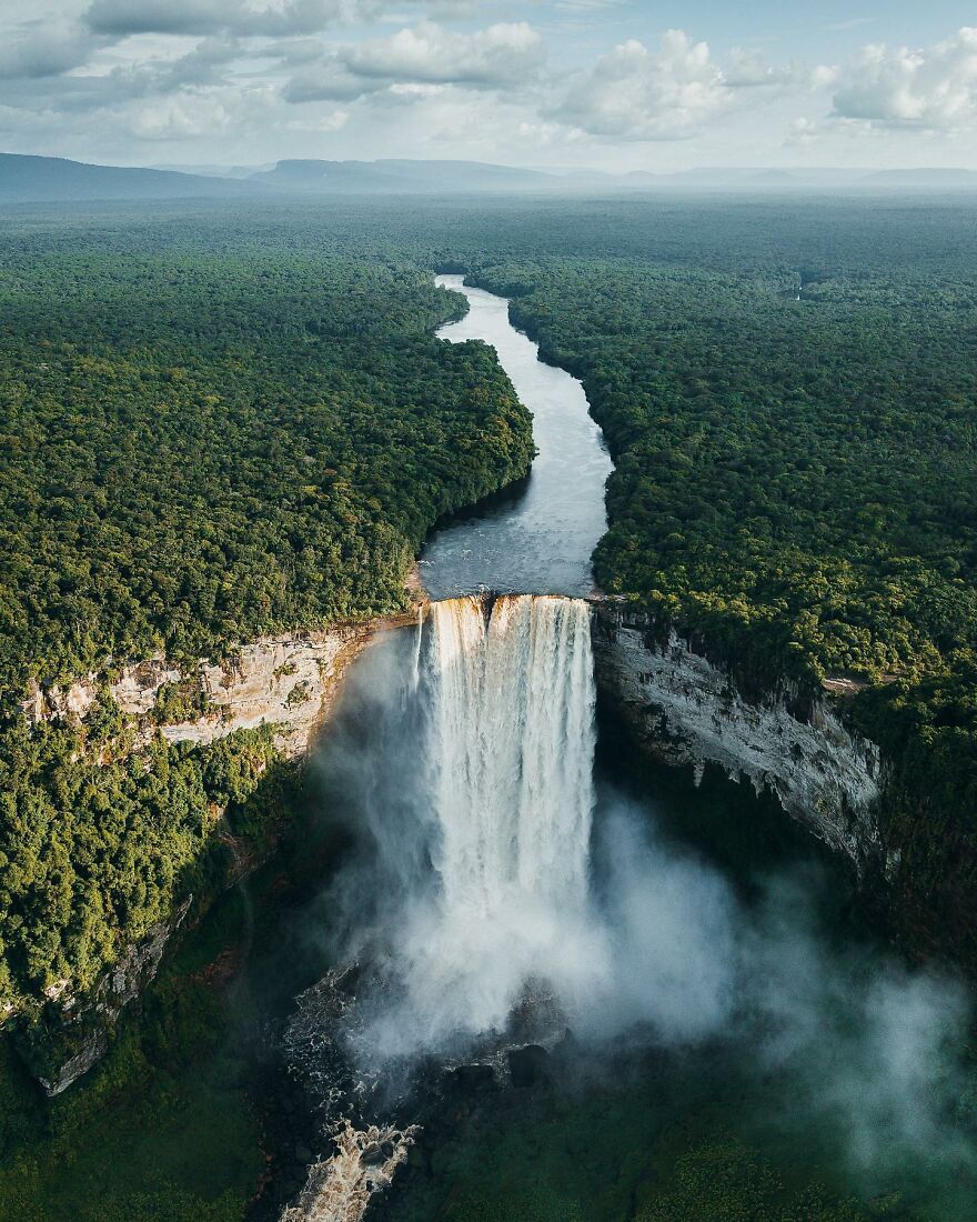 Aerial view of a large waterfall surrounded by dense forest, highlighting top places you should visit at least once.