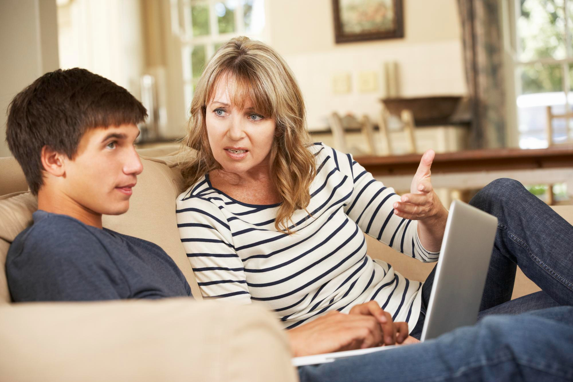 Teen and mother arguing on couch while using laptop, reflecting first car debt trap and $40k loan conflict. Teen and mother arguing on couch while using laptop, reflecting first car debt trap and $40k loan conflict.