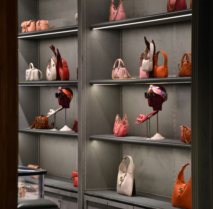 Luxury boutique display of designer handbags and mannequin heads, Greedy Mom theme suggested by opulent purse collection