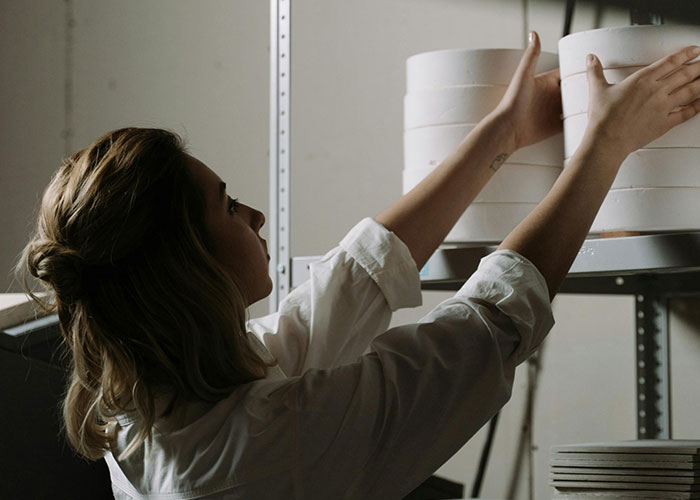 Person organizing white ceramic plates on a shelf, illustrating themes related to neurodivergent experiences.