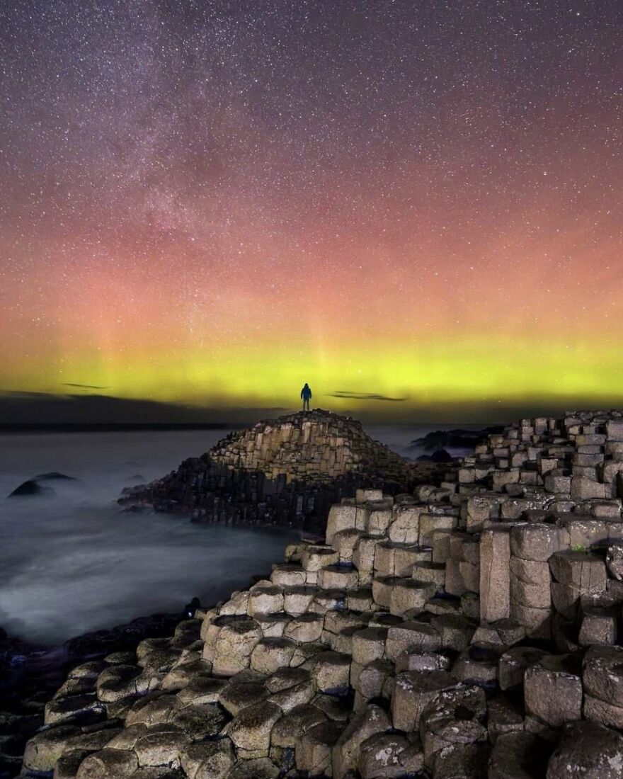 Person standing on unique rock formations under a vibrant night sky, showcasing places to visit at least once in your life.
