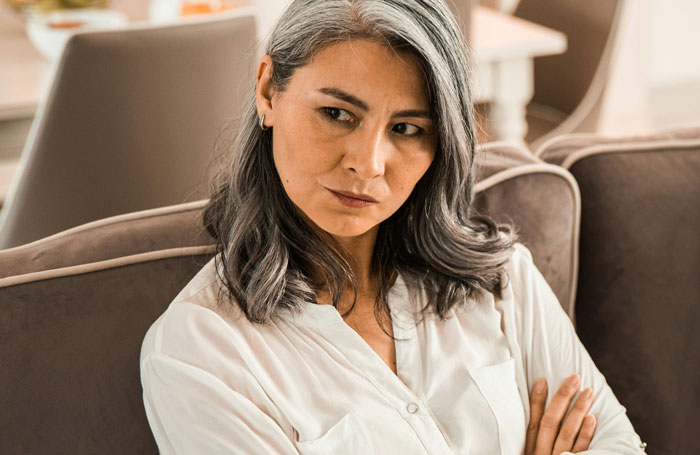 Greedy Mom scowling on couch with arms crossed reacting to inheritance plans