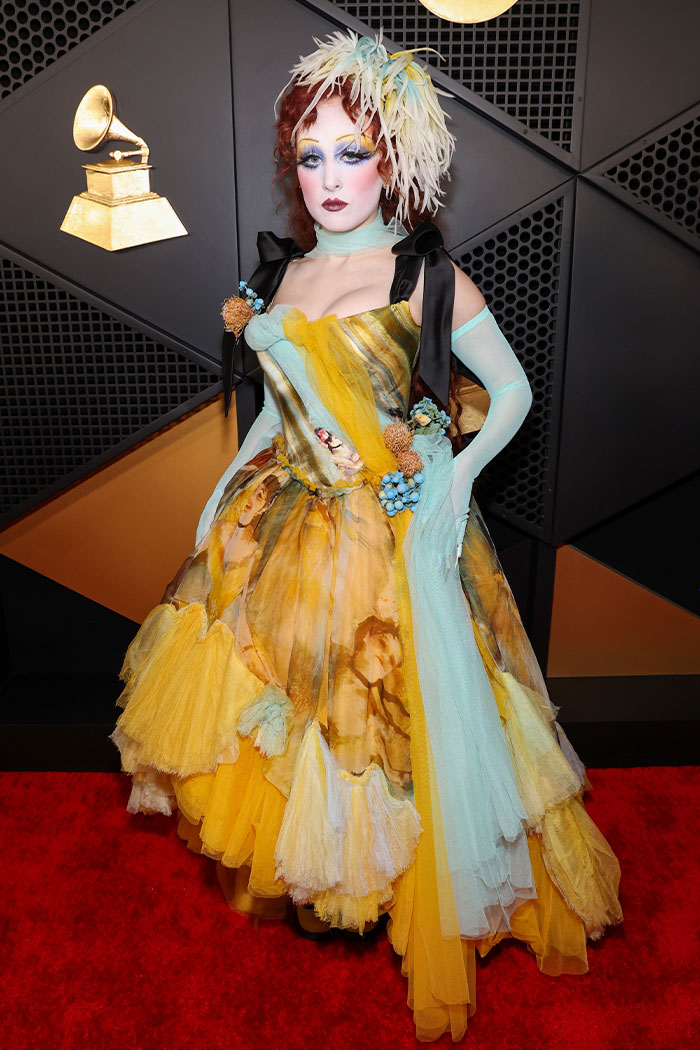 Performer in a dramatic yellow and blue gown with theatrical makeup at a wild Grammys looks red carpet event.