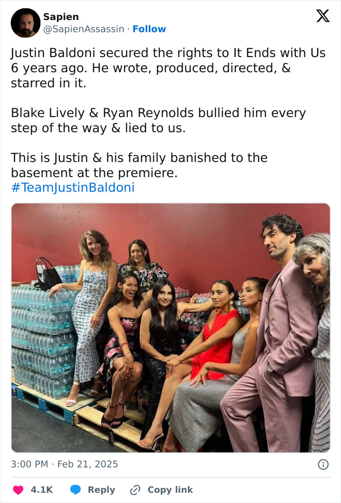 Group of people sitting and standing by a pallet with water bottles, related to British actress Jameela Jamil and Blake Lively conflict.