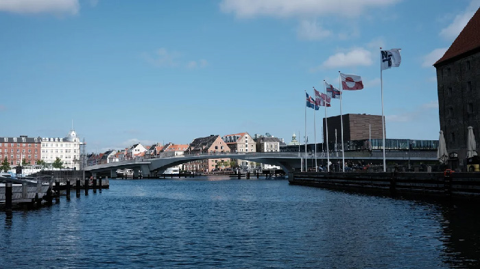 Waterfront view of a European city with flags and buildings, highlighting best countries to raise a family.