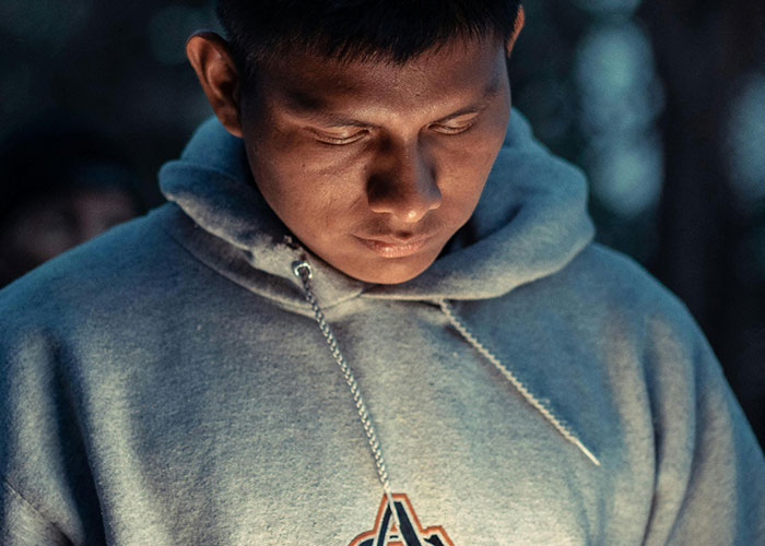 Young man in a hoodie looking down thoughtfully, symbolizing internet troll behavior and online victim impact.