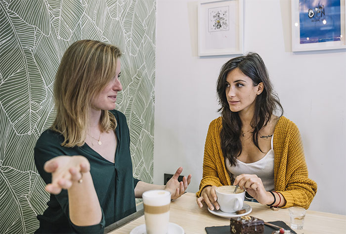 Two women having a serious conversation over coffee, illustrating themes of dressing and being taken seriously in relationships.