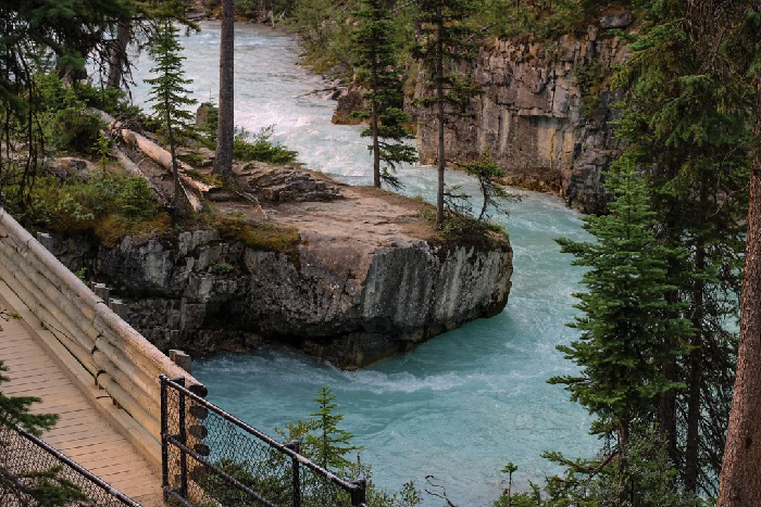 Scenic river flowing through rocky cliffs and pine trees in one of the best countries to raise a family outdoors.