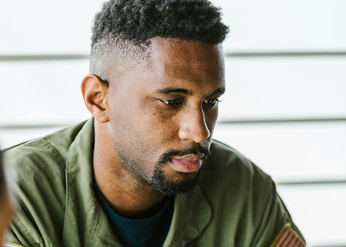 Man with a thoughtful expression reflecting on life changes after learning he is not the biological parent, wearing a green jacket.