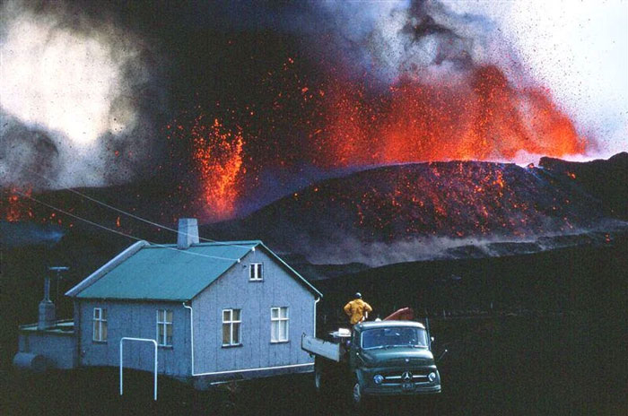 Volcanic eruption near a house with a truck and person, a striking photo from people sharing powerful images of their countries.