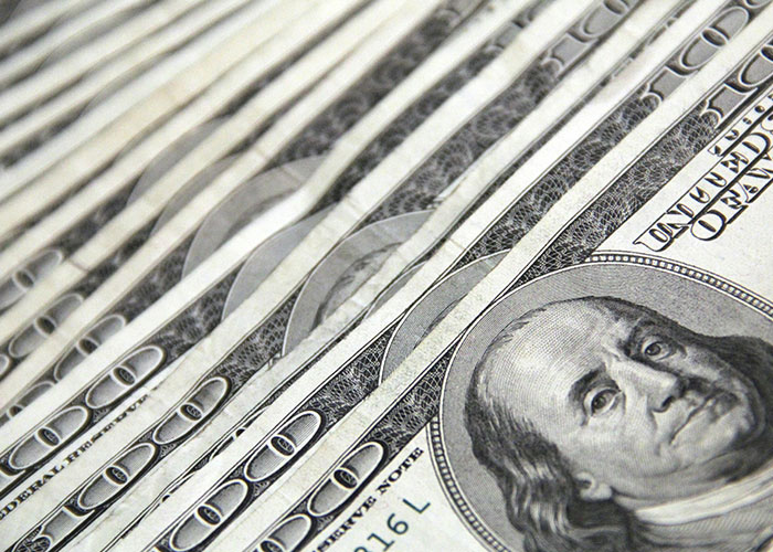 Close-up of stacked hundred dollar bills representing wacky stories about money shared by 51 people.