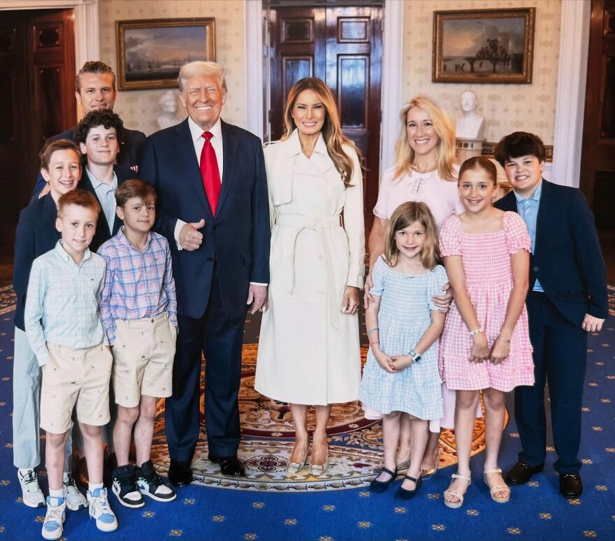 Pete Hegseth&rsquo;s family and children posing with adults in formal room, dressed in smart casual and business attire.