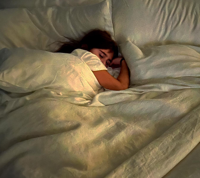 Woman sleeping peacefully in bed, illustrating myths vs reality about women needing more sleep than men.