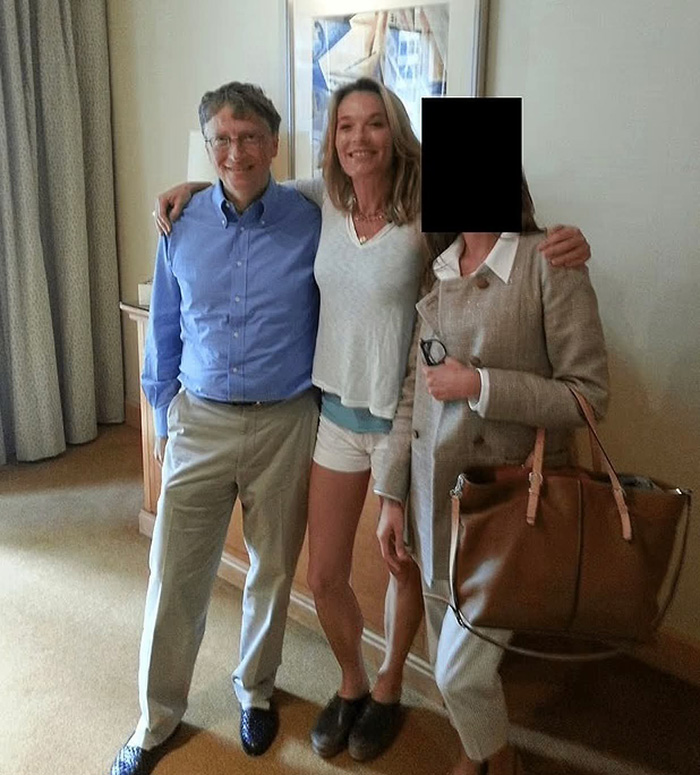 Bill Gates with two women indoors, casual setting, associated with Epstein files and alleged STD and antibiotics claims.