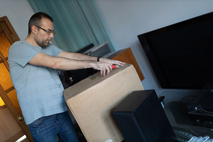 Man packing a large cardboard box in a home, symbolizing a dad facing accusations and his life falling apart