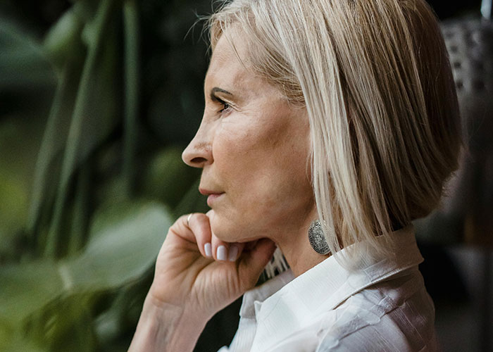 Pensive middle-aged woman with short blonde hair reflecting on a rejected inappropriate baby shower idea.