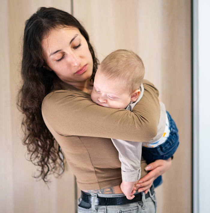 Worried woman holding baby, contemplating her sister who became a tradwife while keeping support fund secret.