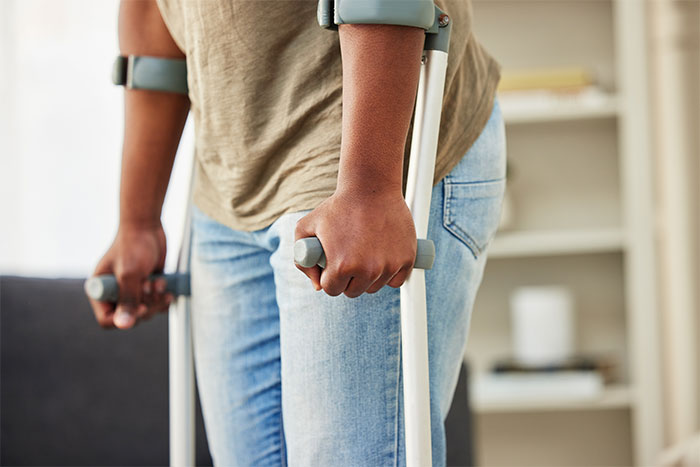 Close-up of woman using crutches indoors, highlighting disability and mobility support in a home setting.