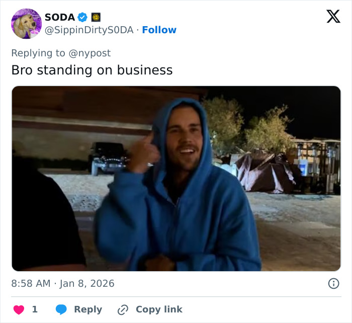 Man in blue hoodie smiling outdoors at night, representing pizzeria owner known for salty replies to harsh online reviews.