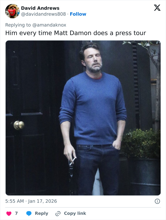 Matt Damon standing outside a dark doorway in casual clothes, looking tired during a press tour.