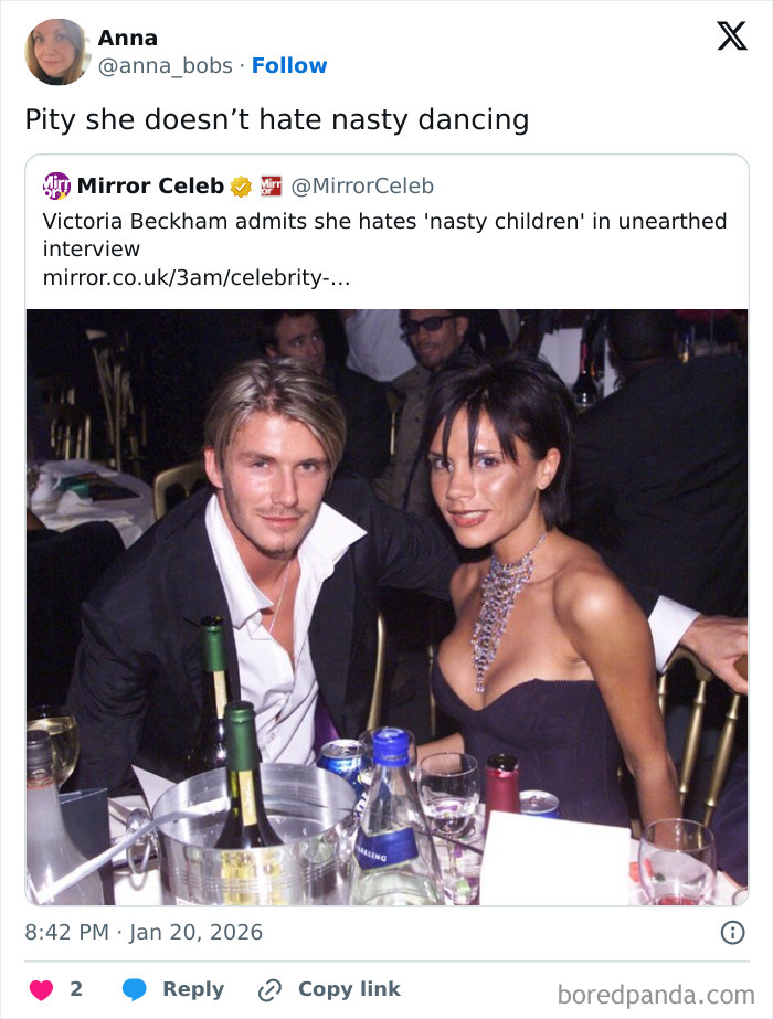 Victoria Beckham and David Beckham posing at a formal event with drinks on the table, spotlight on Victoria.