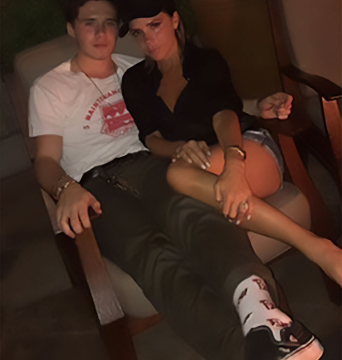 Couple sitting closely on a chair in a dim room, with DJ at Brooklyn Beckham's wedding linked to dance accusations.