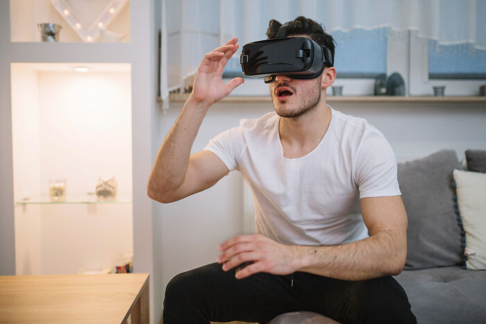 Man wearing virtual reality headset reacting with surprise while sitting on couch, showcasing weird public behavior.