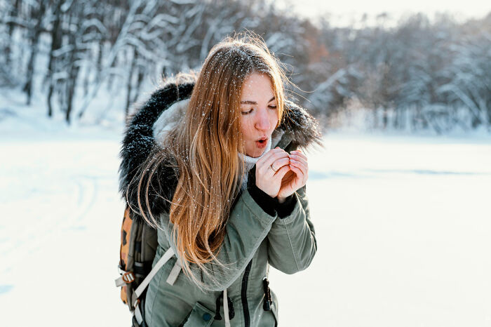 Young woman in winter coat reacting to cold outdoors in snowy landscape, capturing moments that hit people harder than admitted.