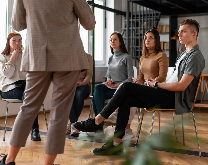 A group of young employees sitting and listening attentively during a discussion of bizarre office rules.