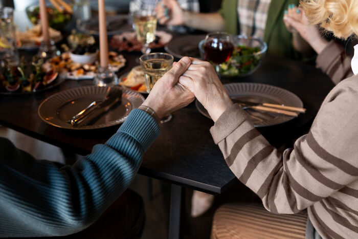 Two people holding hands across a table with empty plates and food, service industry awkward moments.