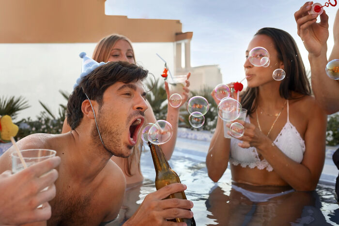 Group of young people in a pool celebrating and blowing bubbles, illustrating fastest times couples said I do and I’m done.