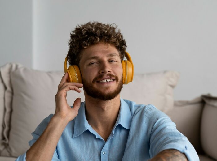 Man with curly hair wearing yellow headphones and a blue shirt, experiencing moments that hit people harder than expected