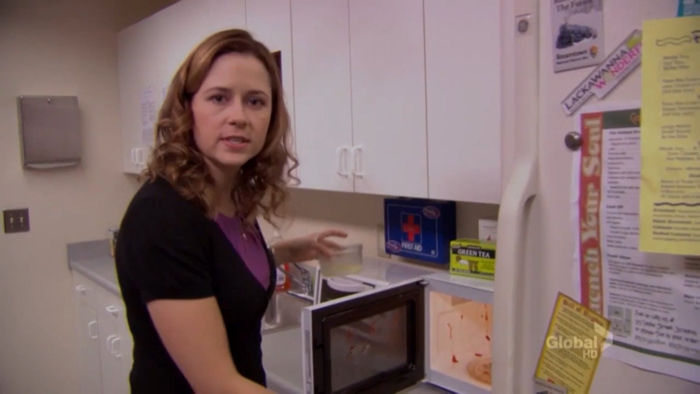 Woman using a microwave in a kitchen, illustrating New Year's resolutions for people who hate New Year’s resolutions.