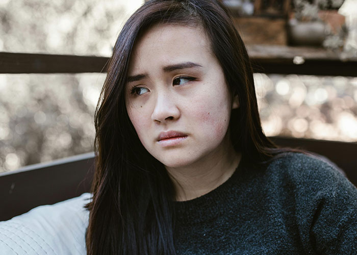 Young woman looking thoughtful and concerned, representing feelings related to being neurodivergent and self-awareness.