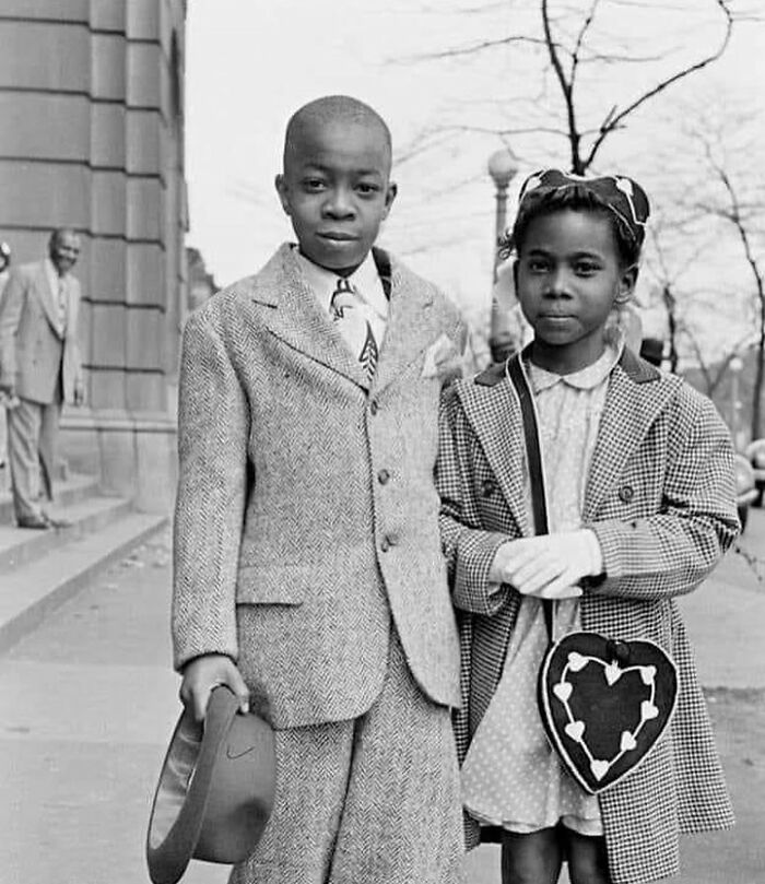 Black and white photo of two children dressed formally, capturing a poignant moment in the history of humanity.