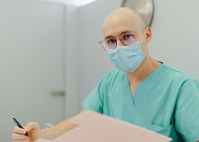 Medical professional in scrubs and mask reviewing patient files, illustrating worst things medical professionals say.