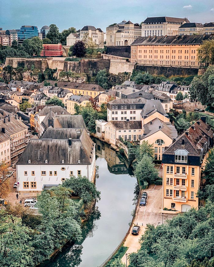 A scenic view of a European town with historic buildings and a river, illustrating countries that sleep the most.
