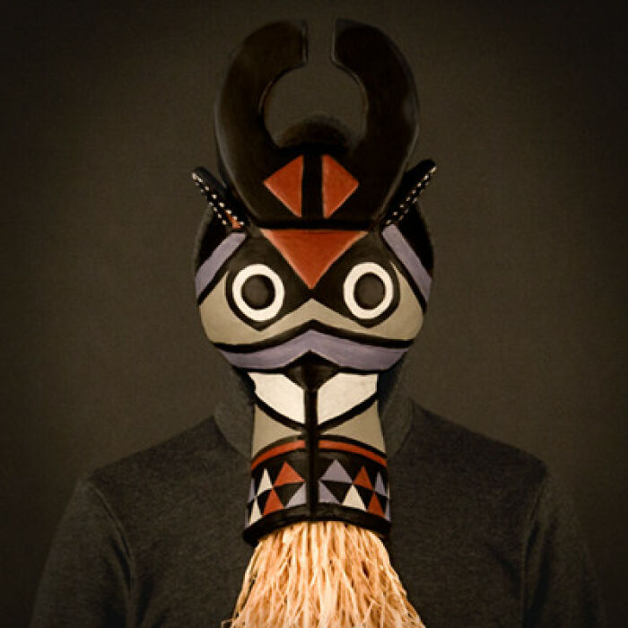 Person wearing a black shirt and an abstract colorful tribal mask as a bad album cover image concept.