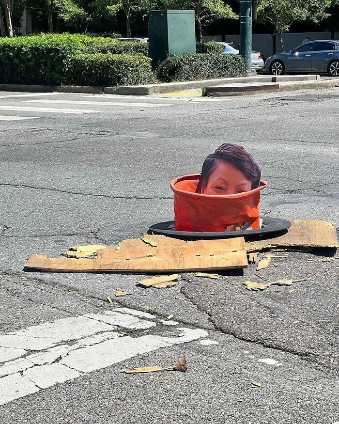 Person's head appearing inside an orange traffic cone in the street, one of the weirdest things found in the streets.