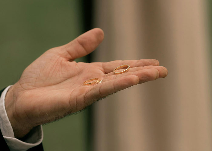 Man’s hand holding two wedding rings, symbolizing the emotional impact of discovering not being the biological parent.