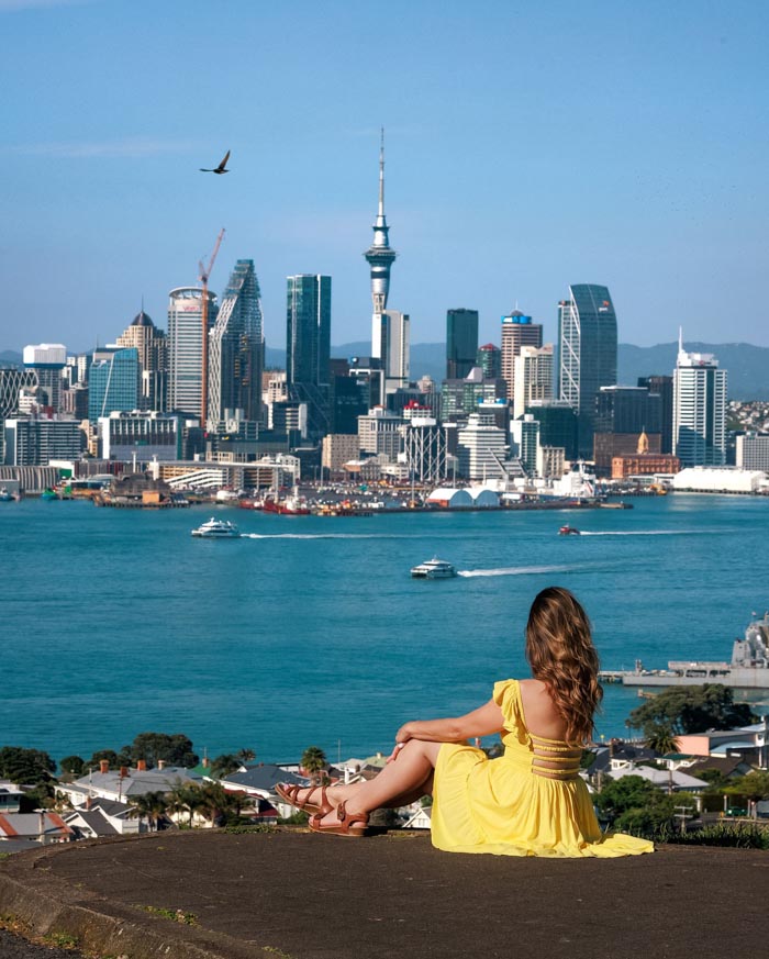 Woman in yellow dress overlooking a city skyline across the water, representing countries that sleep the most according to OECD data.