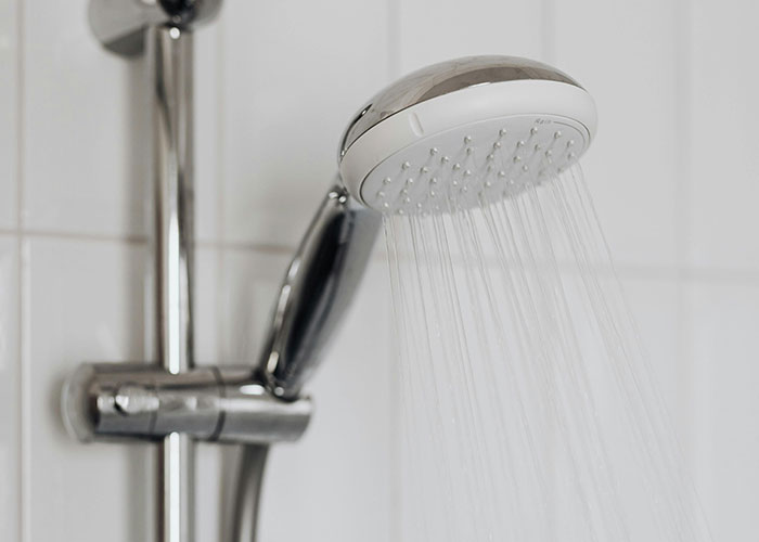 Close-up of a showerhead with water flowing, representing habits neurodivergent people thought were normal.