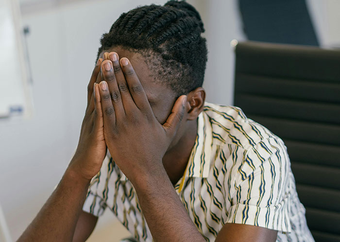 Young man covering his face in frustration, illustrating feelings related to being neurodivergent and misunderstood.