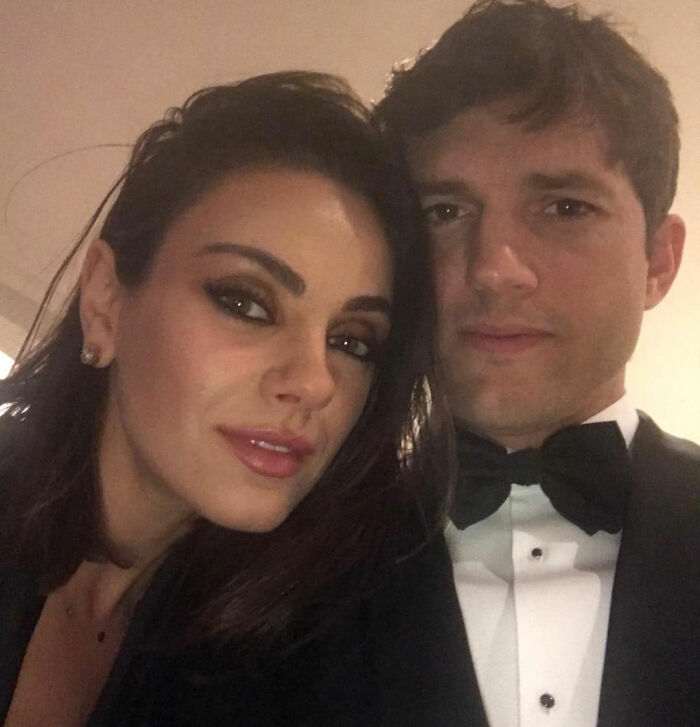 Ashton Kutcher with a rough look posing closely with Mila Kunis at a formal event, sparking speculation.