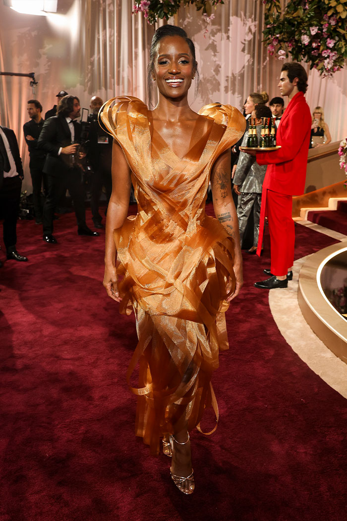 Woman in a bold orange avant-garde dress at the 2026 Golden Globes red carpet fashion disasters event.