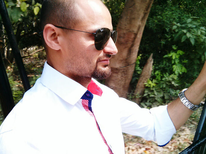 Man wearing sunglasses and a white shirt outdoors in a candid moment reflecting on wedding moments.
