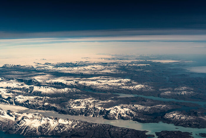 Aerial view of snowy mountain ridges and lakes under a cloudy sky, capturing moments so ridiculous people thought they were pranked.