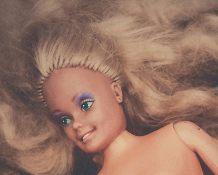 Creepy vintage doll with heavy makeup and tangled hair illustrating weird friends or family